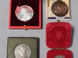 trois médailles d'argent et un écrin en velours rouge posé sur un fond gris