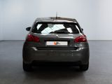 the back end of a grey car in a room with a white wall