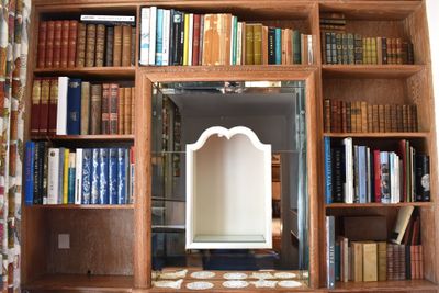 a mirror in the middle of a bookshelf with many books on it