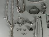 a lot of silver jewelry on a white surface
