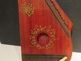 un petit instrument rouge posé sur une table, à côté d'une feuille de papier