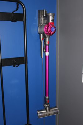 un aspirateur rose à fil, dans un coin d'un mur bleu