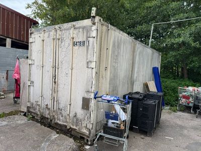 une photo représentant un conteneur maritime devant lequel se trouve un caddie