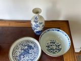 a small table with a vase, bowl, and plate on it