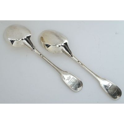 two silver spoons and a spoon rest on a white surface