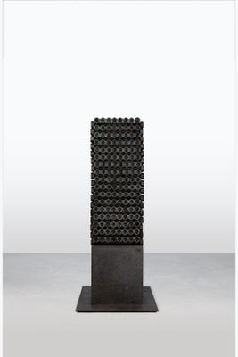 a black sculpture on a metal stand with a white background