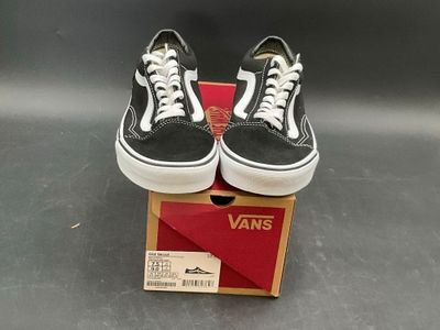 pair of black and white vans sneakers sitting on top of a box