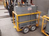 un petit chariot sur lequel est posée une machine, dans un entrepôt