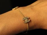 a close up of a woman ' s hand wearing a gold bracelet with a diamond eye charm