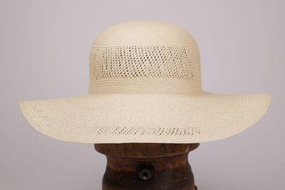 un gros plan d'un chapeau blanc posé sur un support en bois