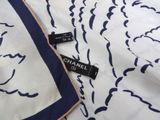 chanel scarf and lipstick on a bed with a blue and white pattern