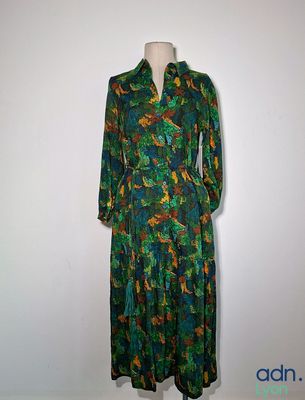 La robe est verte et orange, avec des motifs de feuilles dessus.