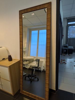 un grand miroir dans un coin de la pièce, à côté d'un bureau