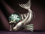 a fish statue with a green glass ball on it