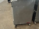 two ovens sitting on wheels in a warehouse with other appliances in the background