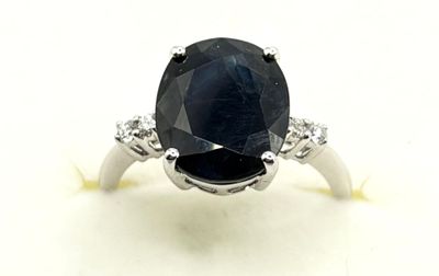 a close up of a sapphire and diamond ring on a white surface