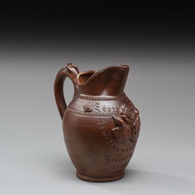 un vieux vase marron orné d'un oiseau, posé sur une table