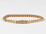 a close up of a gold bracelet on a white surface