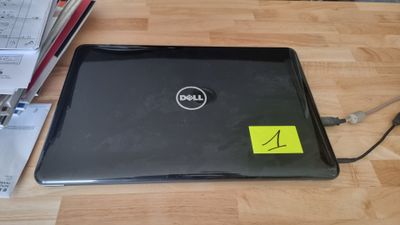 un ordinateur portable Dell, sur lequel est collé un autocollant, posé sur une table