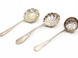 trois cuillères en argent ornées de feuilles, posées sur une surface blanche