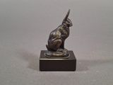 an image of a bronze statue of a cat sitting on top of a wooden base