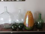 many glass vases on a table with a mirror in the background