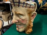une statue représentant un homme fumant la pipe à côté d'un vase