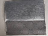 silver leather wallet on a white surface with a small hole in the middle