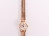 une montre en or sur une surface blanche avec un fond blanc