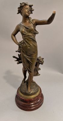 statue en bronze d'une femme tenant un oiseau sur une base en bois