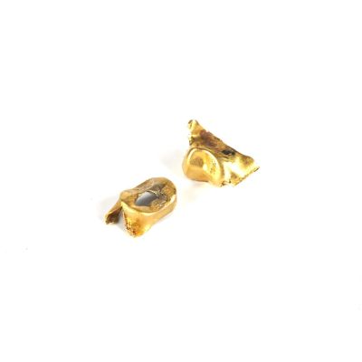 une paire de boucles d'oreilles en or sur une surface blanche