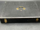 a black suitcase sitting on a table with a gold handle