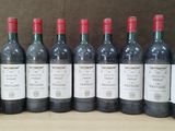 six bouteilles de vin rouge alignées sur une table en bois