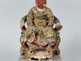 an old statue of a man sitting on a chair with a cat