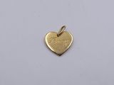 a gold heart shaped charm with the word love written on it