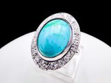 a close up of a ring with a turquoise stone surrounded by diamonds