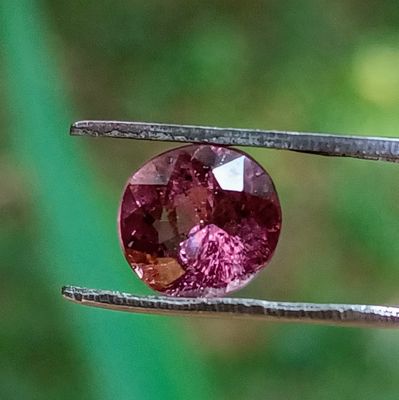un gros plan d'un diamant rose tenu par une paire de pinces