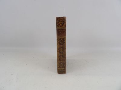 un vieux livre posé sur une table à côté d'un mur blanc