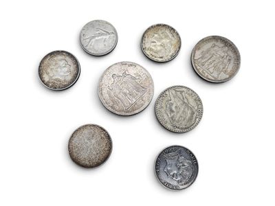 Plusieurs types de pièces de monnaie sont disposées en cercle sur une surface blanche.