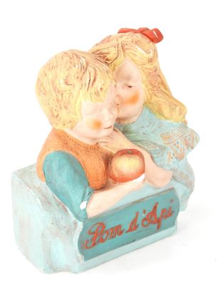 une figurine représentant un garçon et une fille tenant une pomme