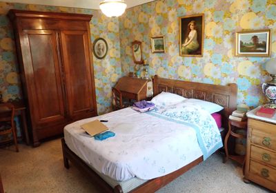 une chambre avec un lit, des commodes et des tableaux accrochés au mur
