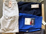 plusieurs paires de pantalons pour homme posées sur une caisse en bois