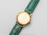 a close up of a watch on a white surface with a green strap