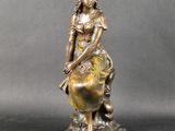 une statue en bronze représentant une femme assise sur un globe terrestre