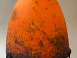 an orange vase with a black and white design on it