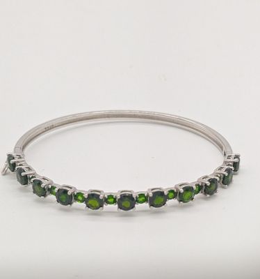 un gros plan d'un bracelet orné de pierres vertes sur fond blanc