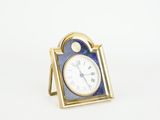 an image of a small blue and gold clock on a white surface