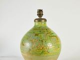 un vase vert posé sur une surface blanche, surmonté d'une lampe