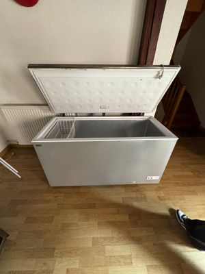 un congélateur à porte ouverte posé sur un sol en parquet