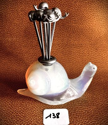 a glass vase with a bird on top of it on a table